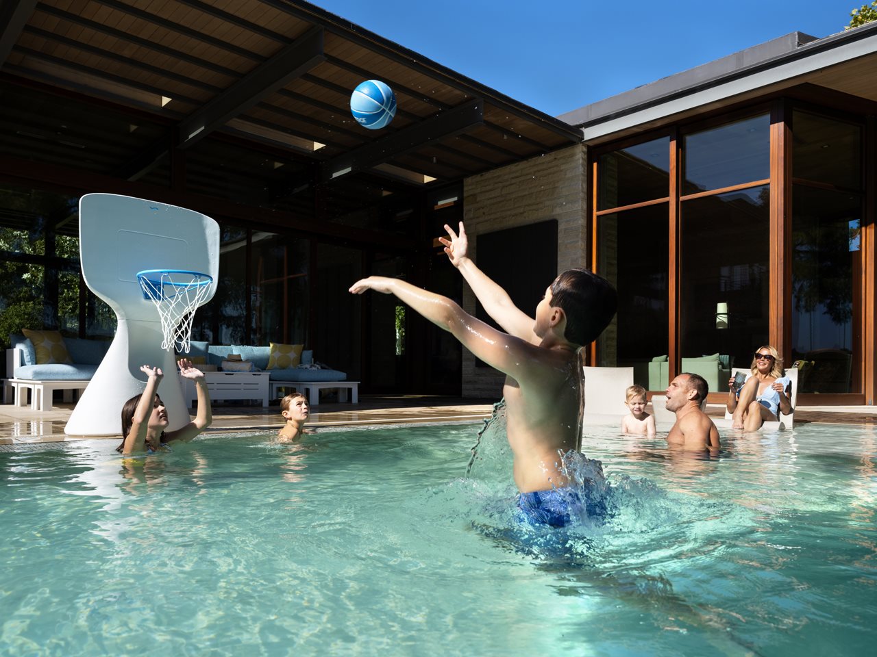 Kids playing basket ball in the backyard pool.