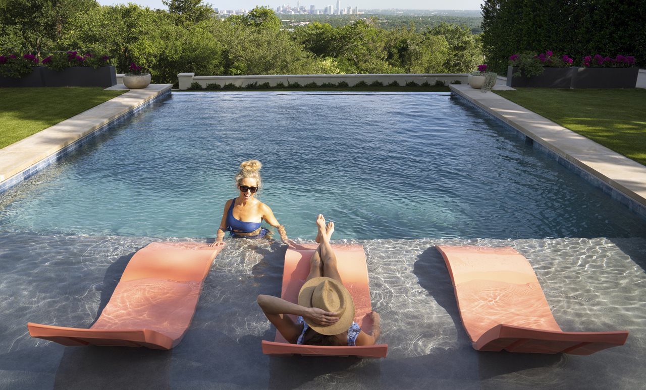 Two woman in a backyard pool.