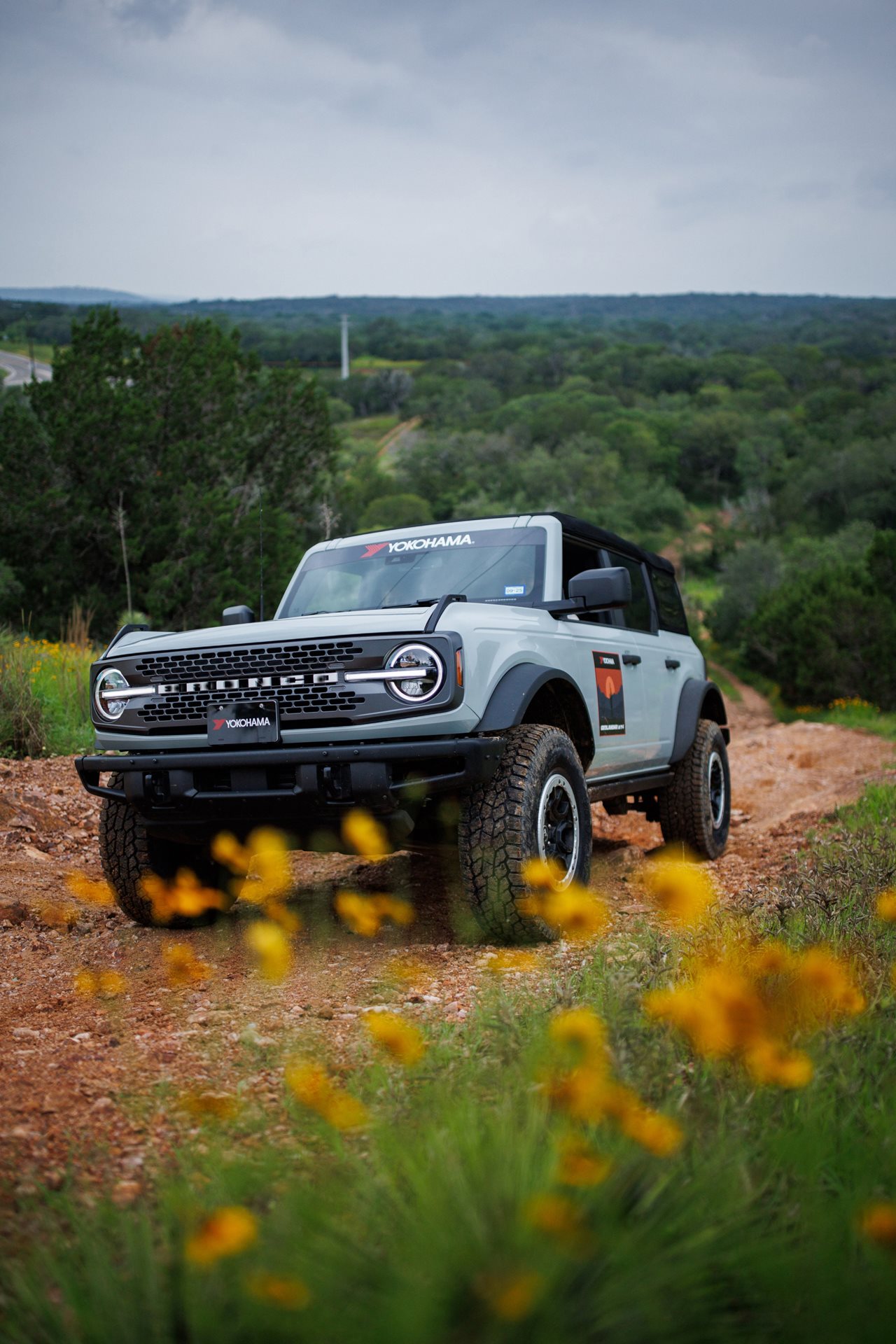 Large gray truck driving on a rock road in the woods.