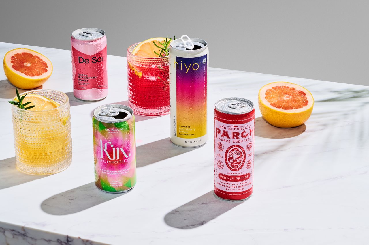 Cans of open beverages and glasses with ice and beverages on a table