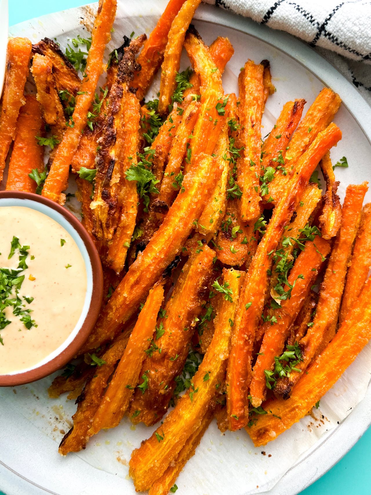 Plate of baked carrot fries and a side of dip.