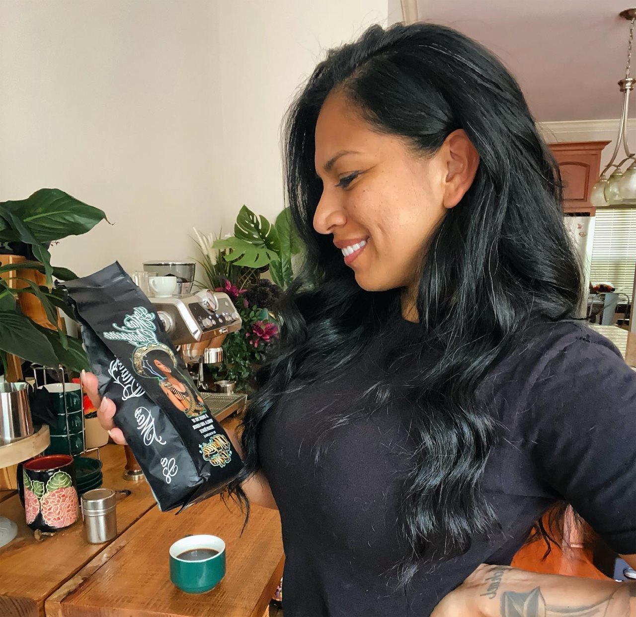 Sgt. 1st Class Elizabeth Calderon holding a package of coffee beans next to a coffee maker.