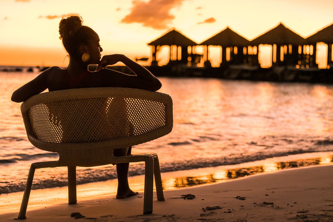 Woman relaxing oceanside sunset at the Renaissance wind creek aruba resort.