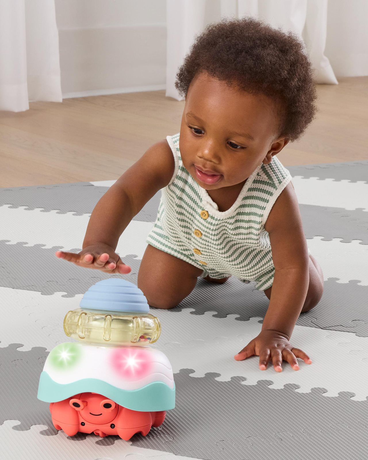 Adorable baby playing a floor toy that looks like a crab.