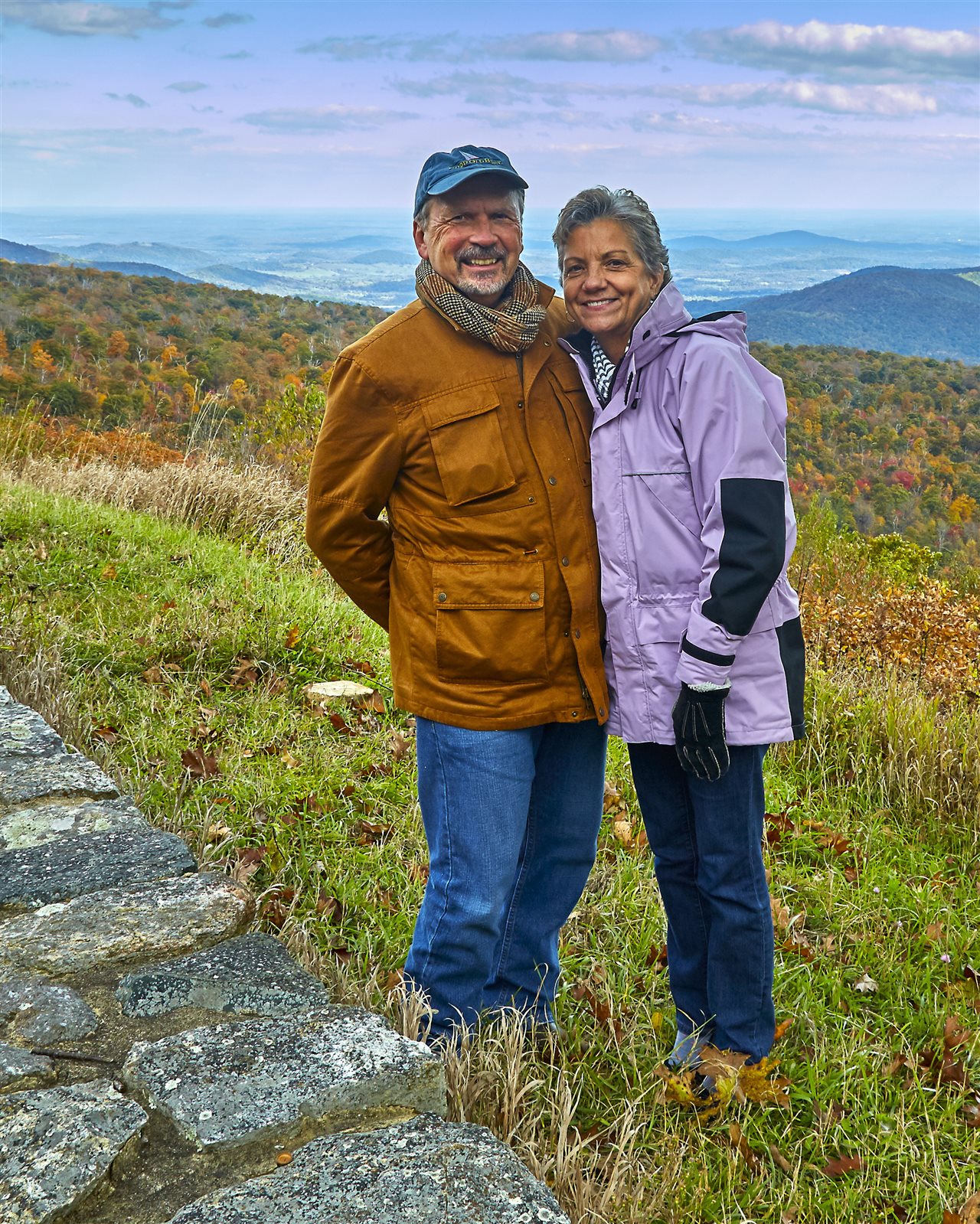 Bob and Bev wearing jackets enjoying a mountainous vista during Autumn.