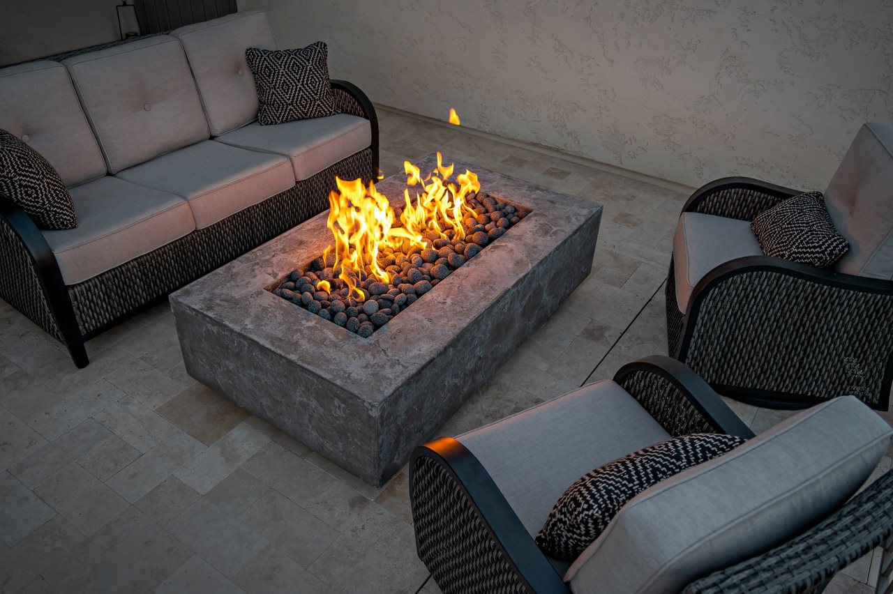 Back yard fire feature surrounded by cozy, comfortable outdoor wicker furniture.