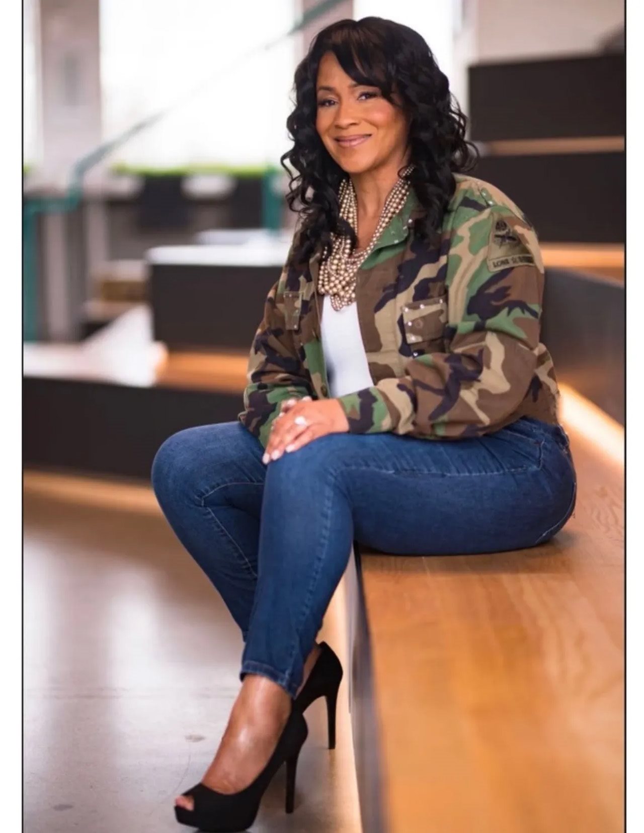 Althea Williams wearing her Army jacket and sitting on a flight of stairs.