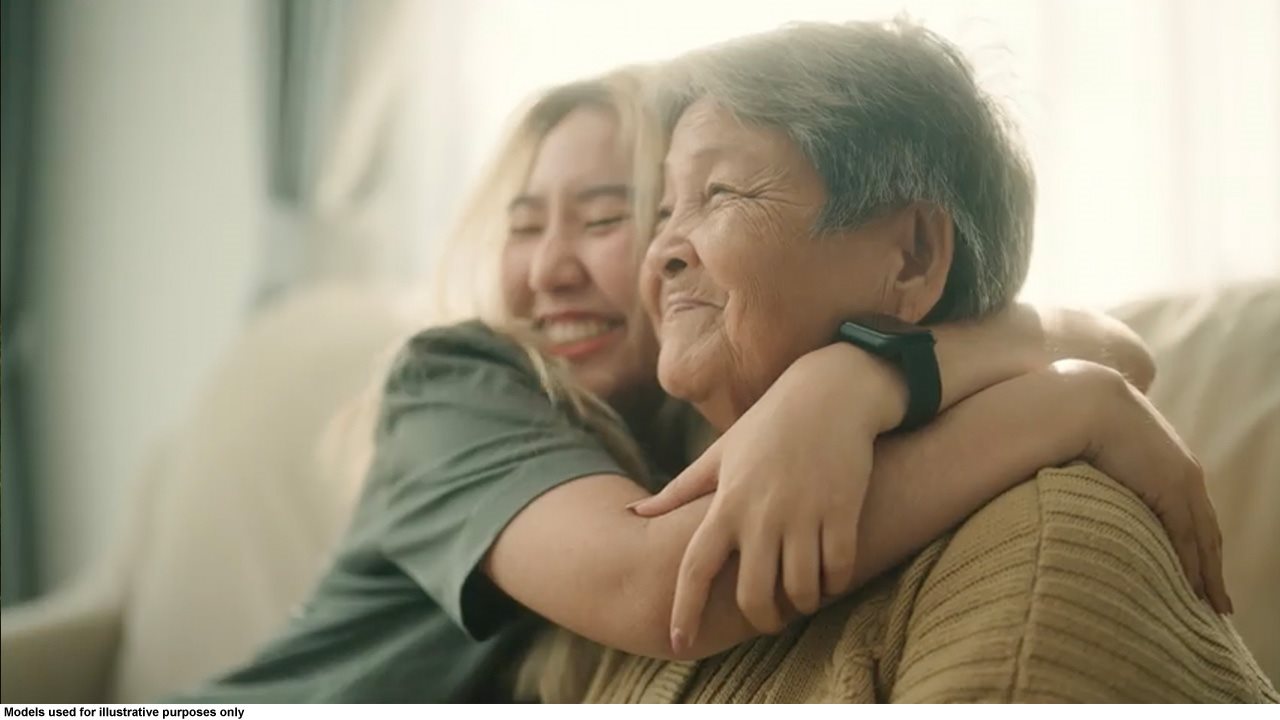 Younger woman hugging older woman while sitting on the couch.