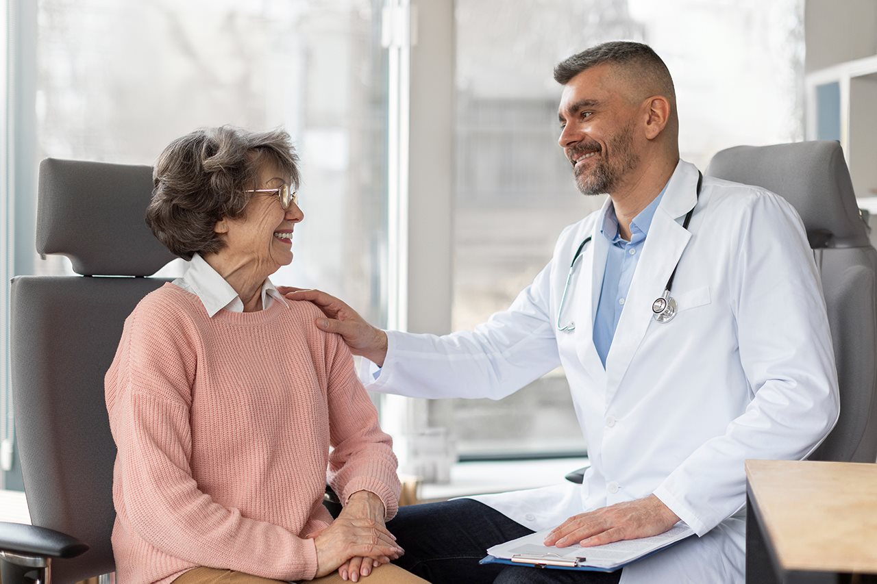 Male doctor consulting an older female patient in his office.