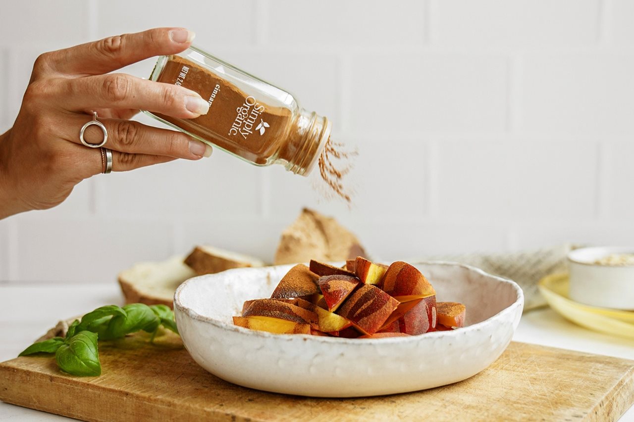Woman sprinkling Simply Organic Spices on salad.