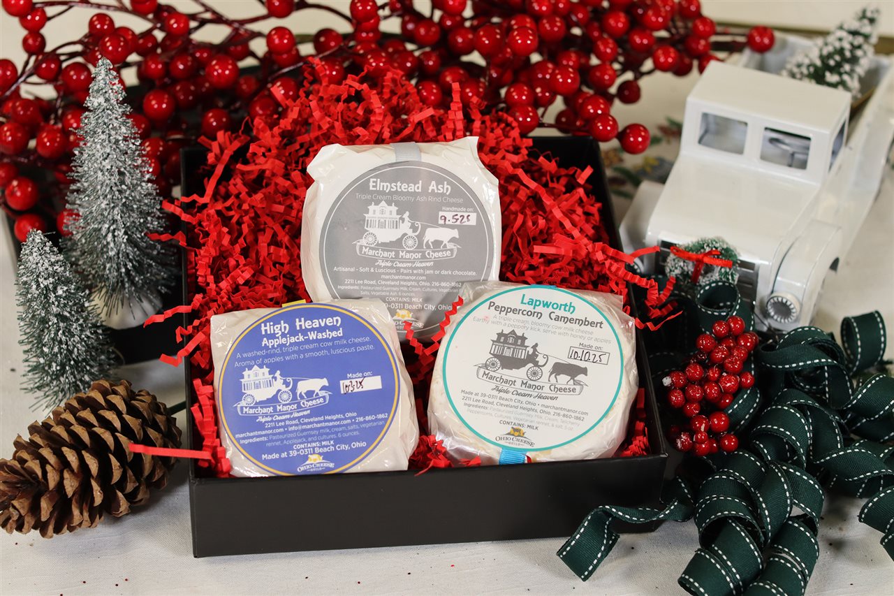 Marchant Manor Cheese Holiday Gift Pack includes: Limited Edition Lapworh Holiday Red Pepper Camembert, High Heaven Applejack-Washed cow milk cheese, and Elmstead Ash Cow Triple Cream Bloomy Ash Rind cheese.