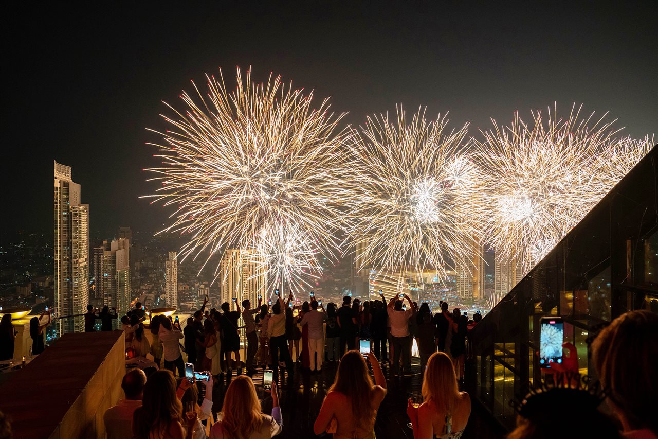 Large group of people enjoying New Years Eve fireworks from Tower Club dome in lebua. Bangkok.