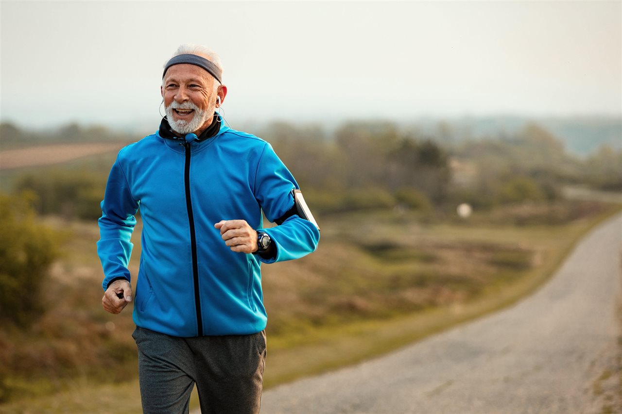 Senior man jogging down a country road.