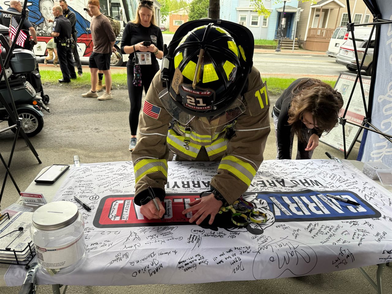 Fire-fighter signing a memorial banner. Carry The Load is a trusted organization that supports those who serve.
