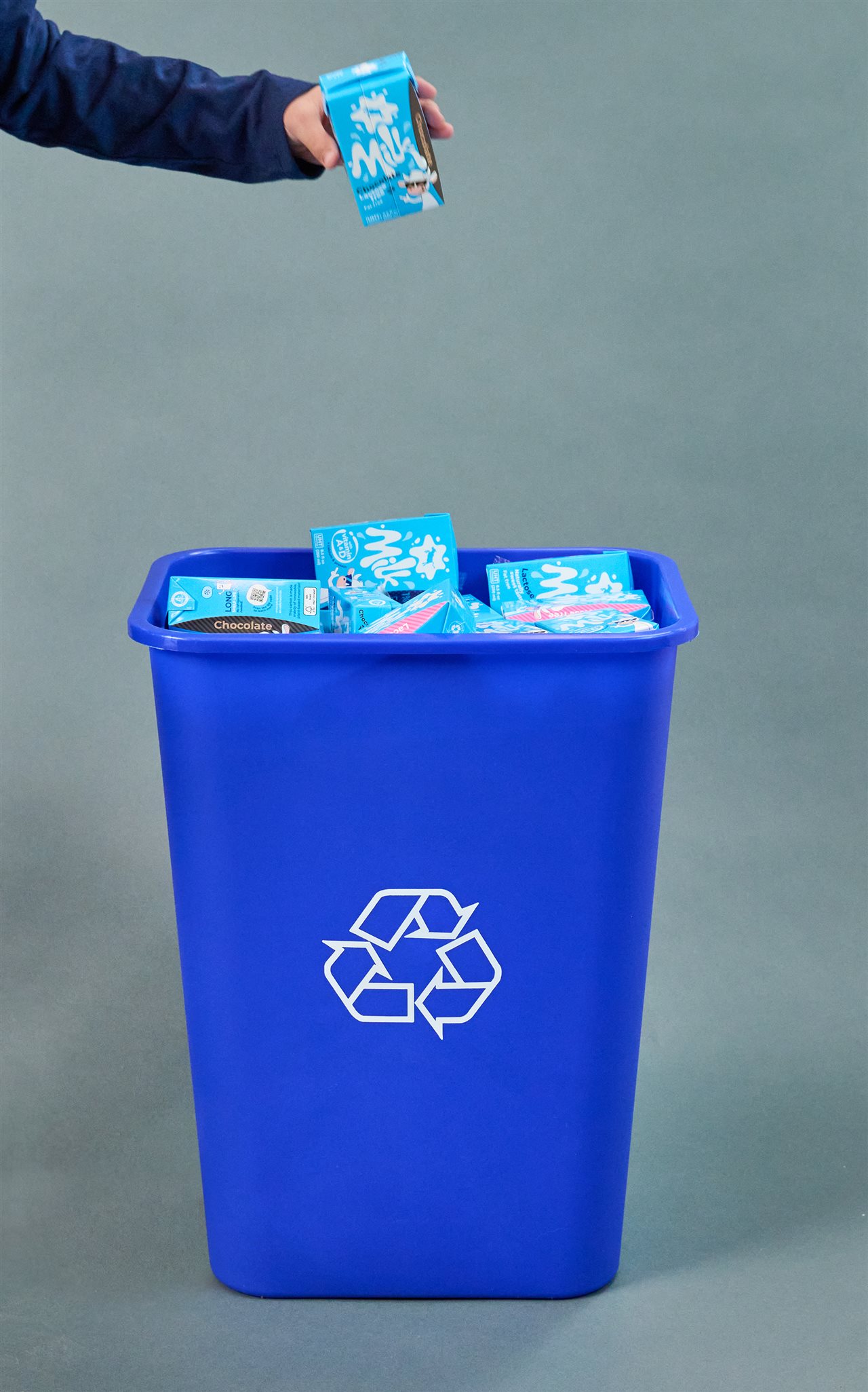 Man dropping a Tetra Pak carton into a recycling bin.
