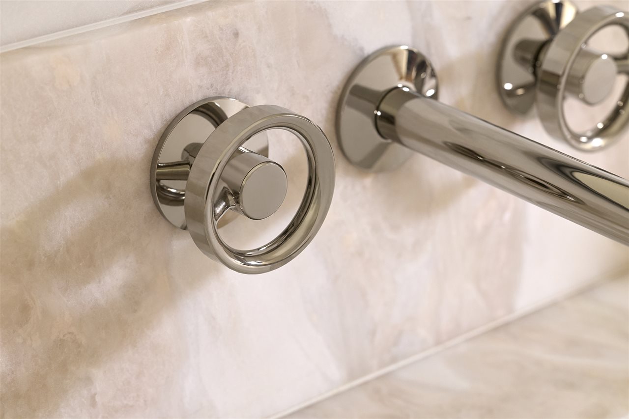 A set of ring-shaped faucet knobs on a marble tub.