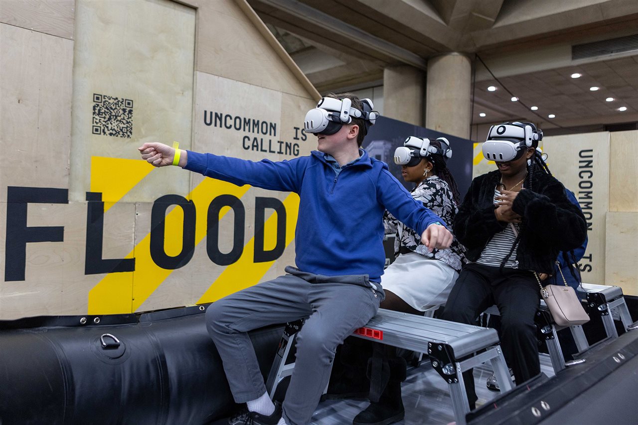 Three kids playing a virtual game with tyep in background
