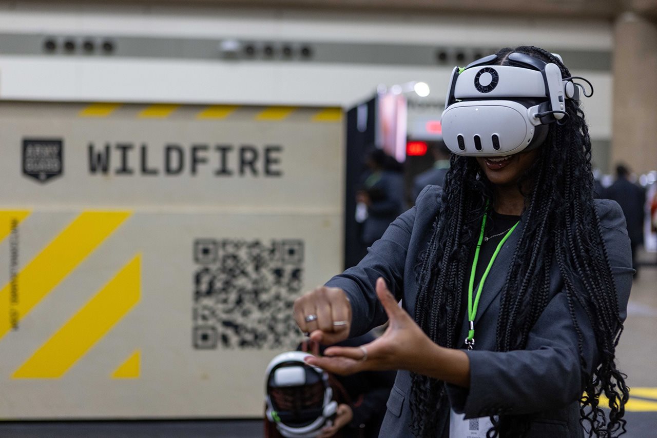 A woman wears a VR headset in front of a sign reading