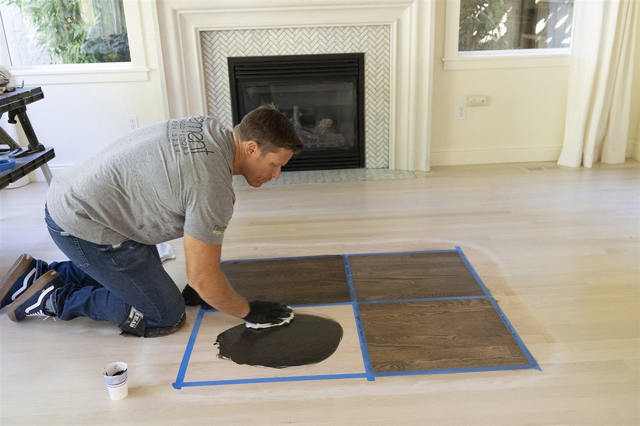 Man testing stain on a wood floor. A Bona Certified Craftsman ensures your floor will be properly and beautifully refinished.